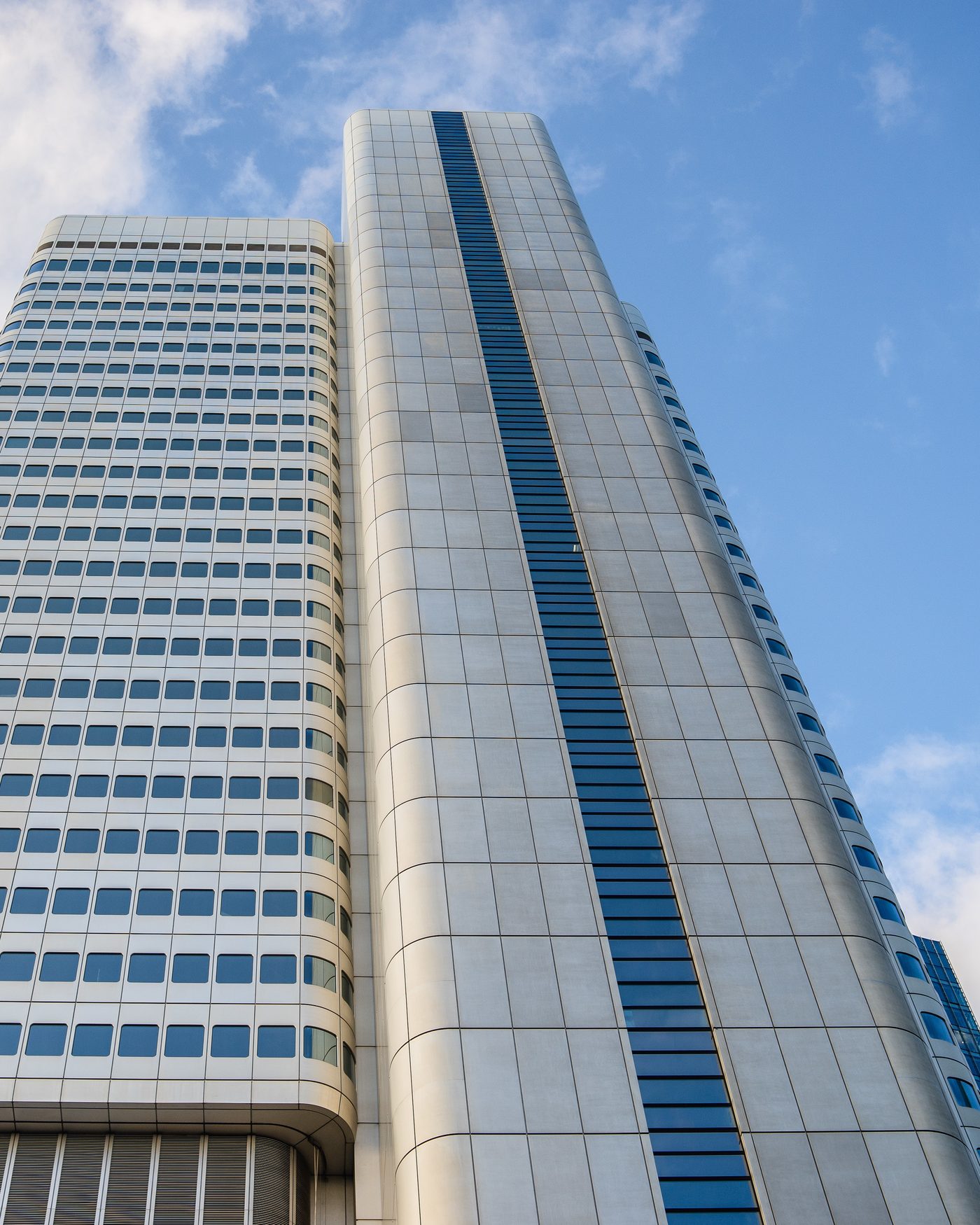 Fachada de um edifício corporativo envidraçado, vista de baixo contra o céu.